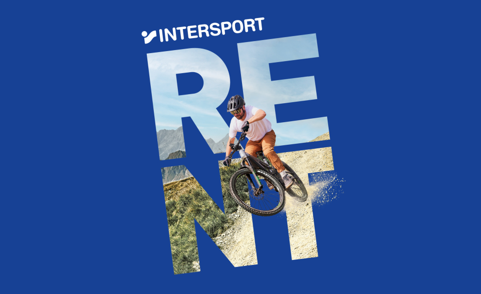 A cyclist wearing a helmet rides energetically down a dirt trail, with "INTERSPORT RENT" in large letters overlaid, set against a blue background.
