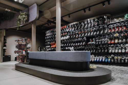 Innenausstattung eines Skischuhgeschäfts mit Ausstellungsregalen und modernem Sitzbereich.