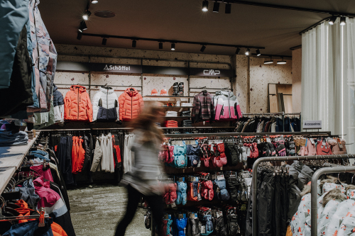 Innenraum eines Outdoor-Bekleidungsgeschäfts mit Regalen voller Jacken, Handschuhe und Winterbekleidung.