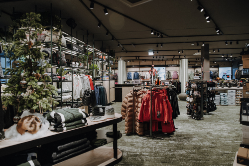 Exklusives Bekleidungsgeschäft mit Weihnachtsbaum, Kleiderständern und Verkaufsdisplays.