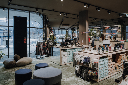 Modernes Ladengeschäft mit Kleiderständern, Schuhauslagen und Sitzbereich.