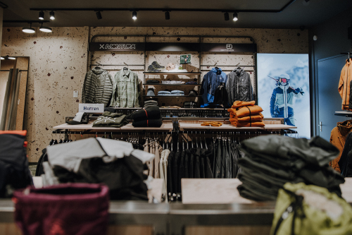 Innenraum eines Outdoor-Bekleidungsgeschäfts mit Jacken, Hemden und Bekleidung in Ausstellungsregalen.